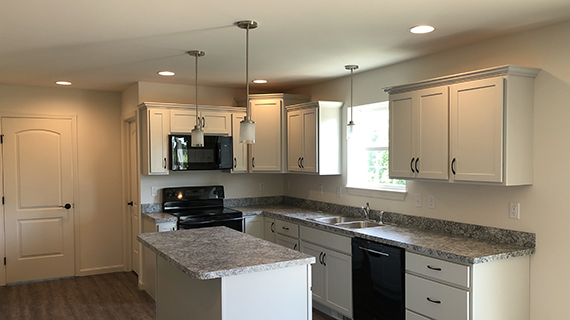 kitchen with gray countertop and white cabinets. Island with hanging overhead lights
