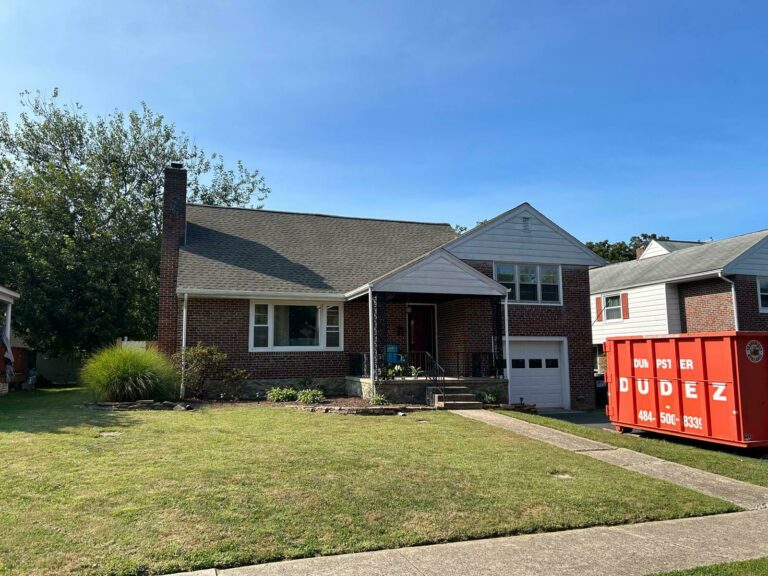 A home with a completed new roof installation, with a red dumpster outside to keep the property clean after construction in Reading PA